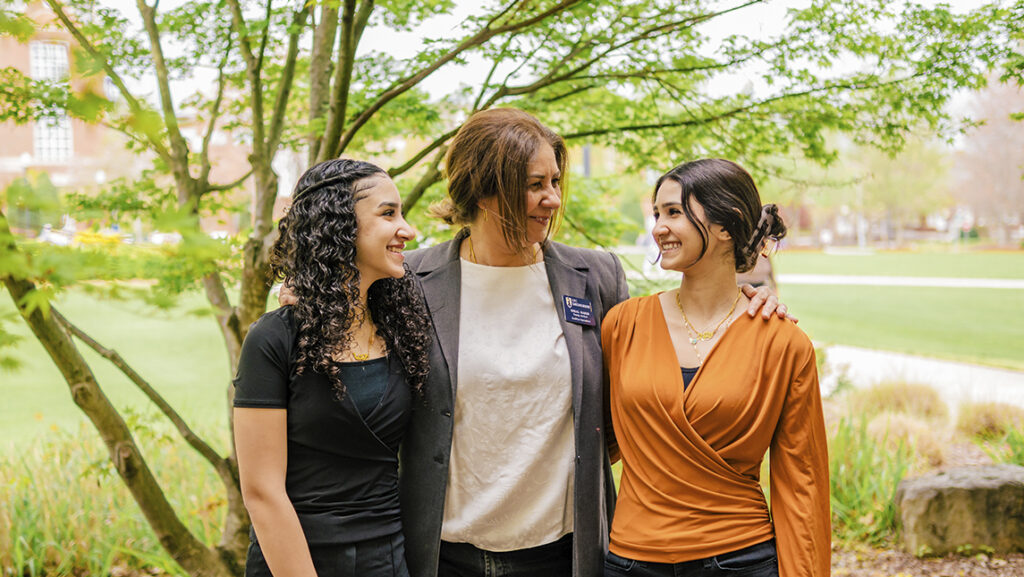 Nihal Al Raees stands under a tree on UNCG campus with her two daughters