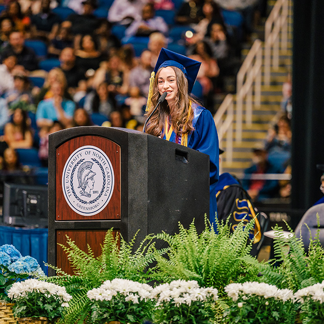 Female student speaks at commencement podium.