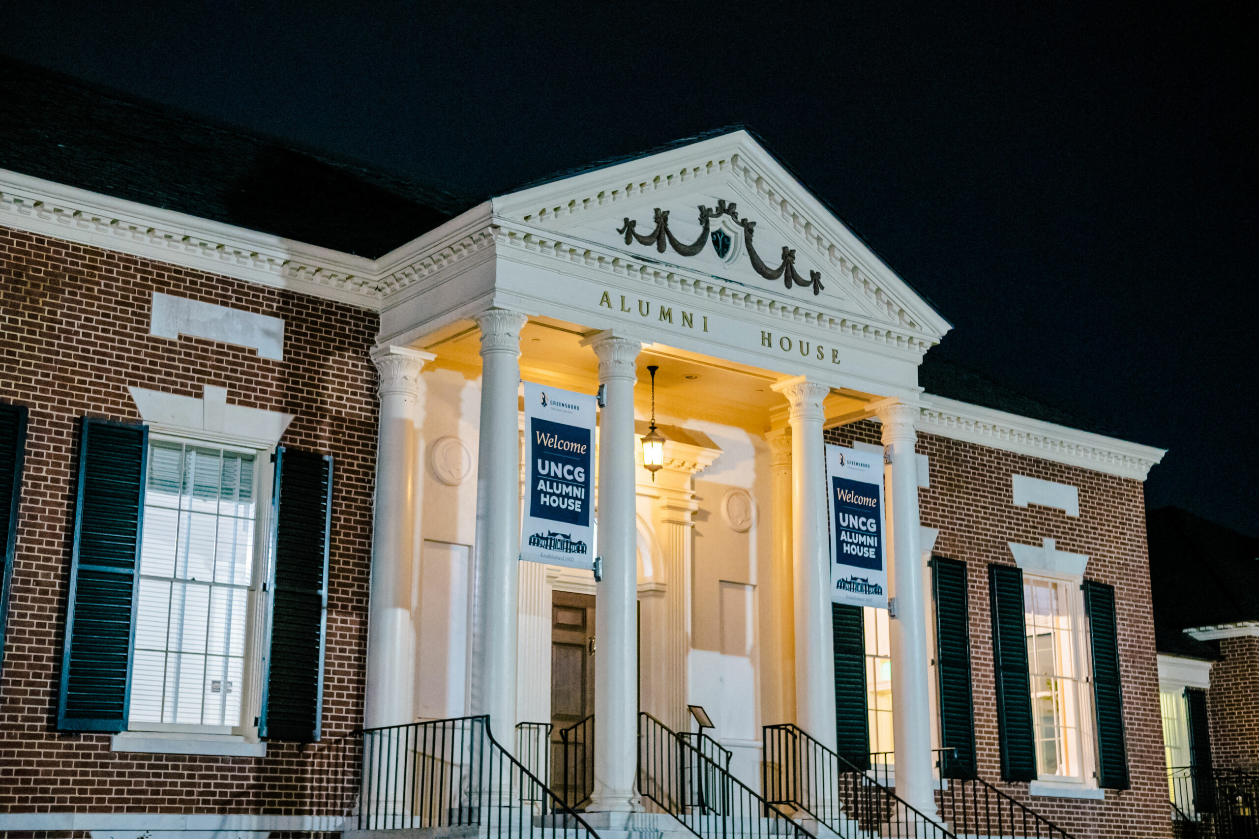 Night photo of the front of the Alumni House.