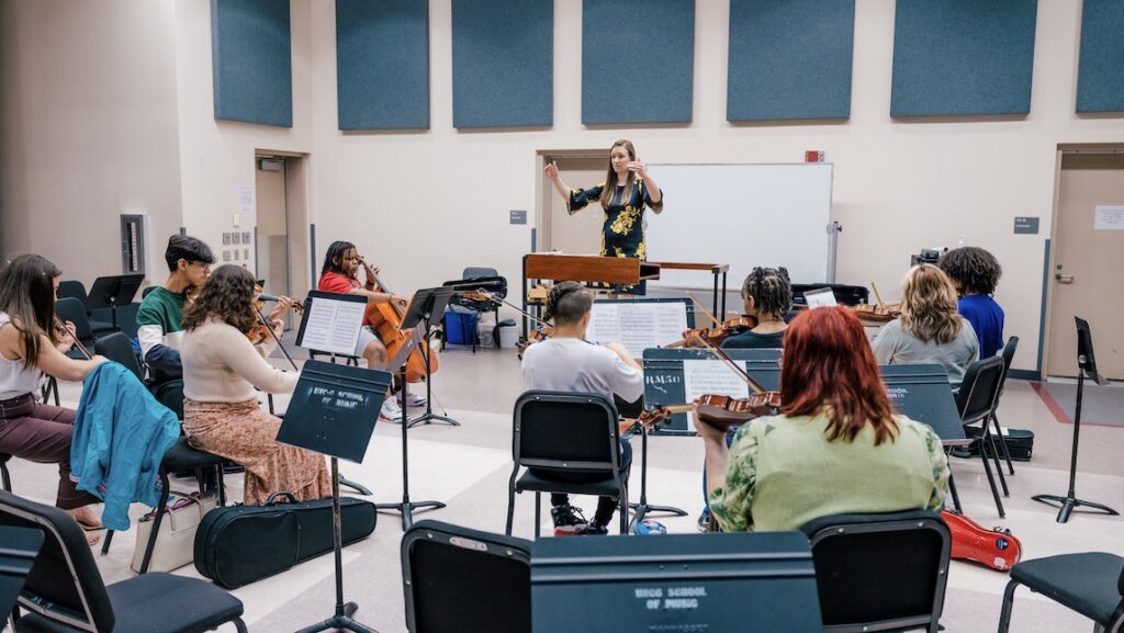 Music professor teaching group of string instrument students.