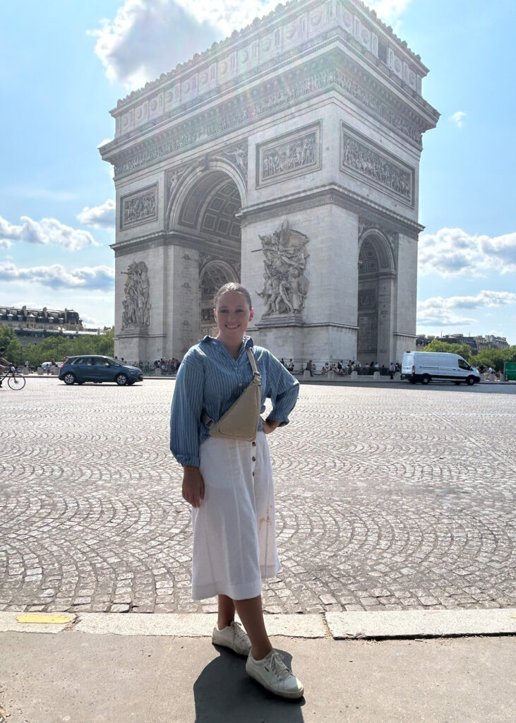 Young girl posing in front of the Arc de Triomphe in Paris. 