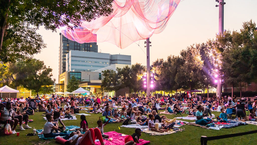 Crowds of people with blankets and camping chairs on the lawn in Lebauer Park.