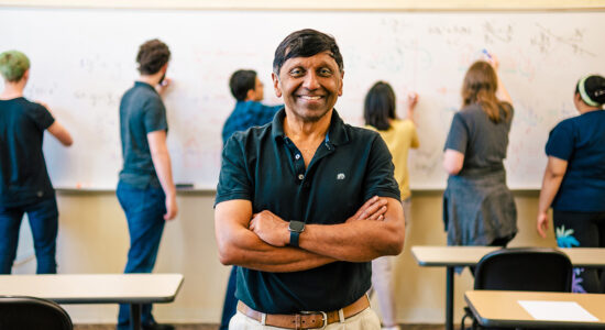 Dr. Ratnasingham Shivaji stands in the classroom while his UNCG students work equations at the whiteboard.
