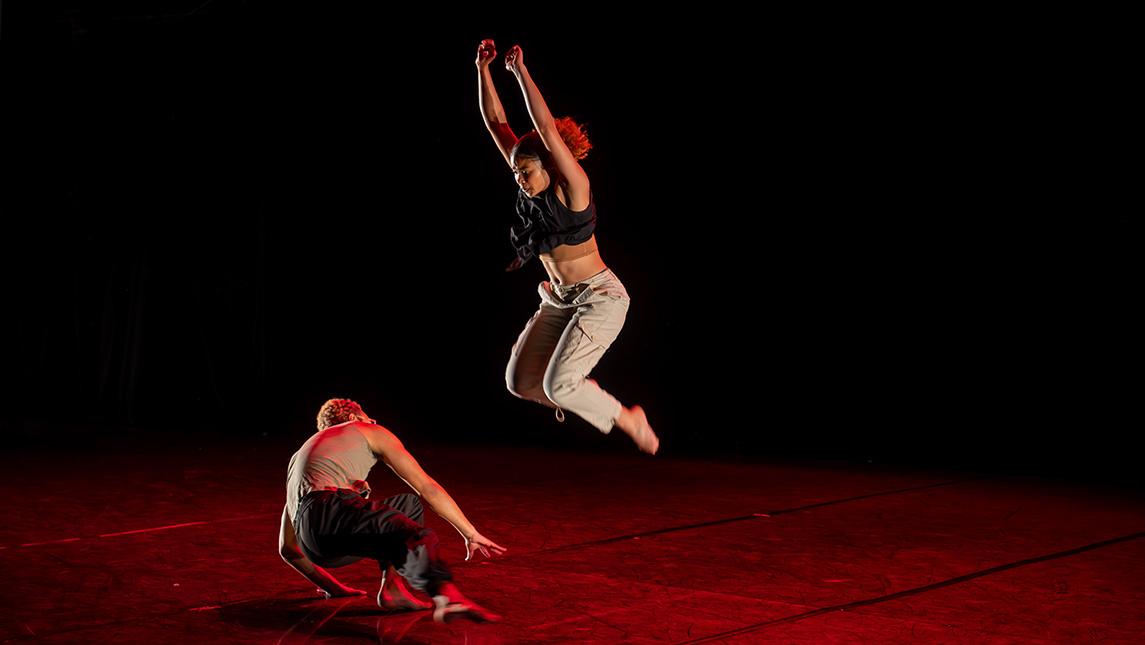 A dancer jumps into the air while another is on the ground