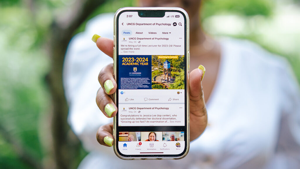 A UNCG student holds up a phone.