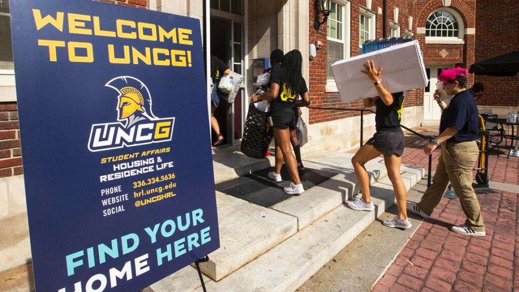 Students haul belongings into residence hall during move-in.