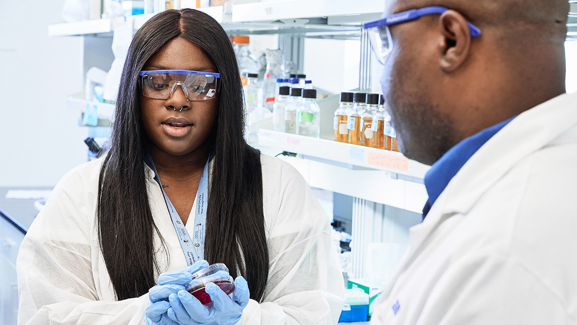 Student studies a lab sample with her professor in the UNCG biology lab.