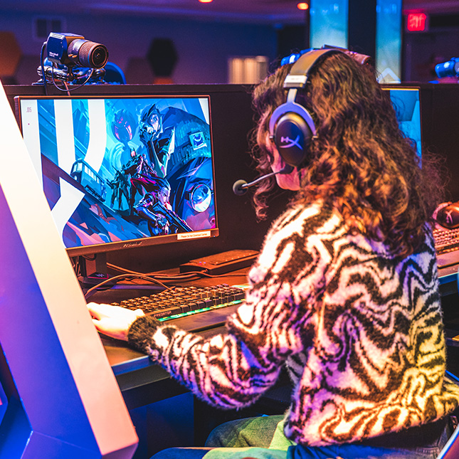 Girl sits at a gaming station in the esports arena. 