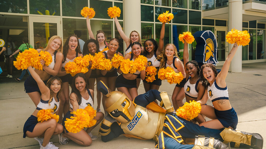 UNCG mascot Spiro poses in front of the cheerleaders.