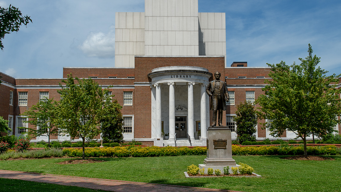 The UNCG library and the McIver statue on a summer day.