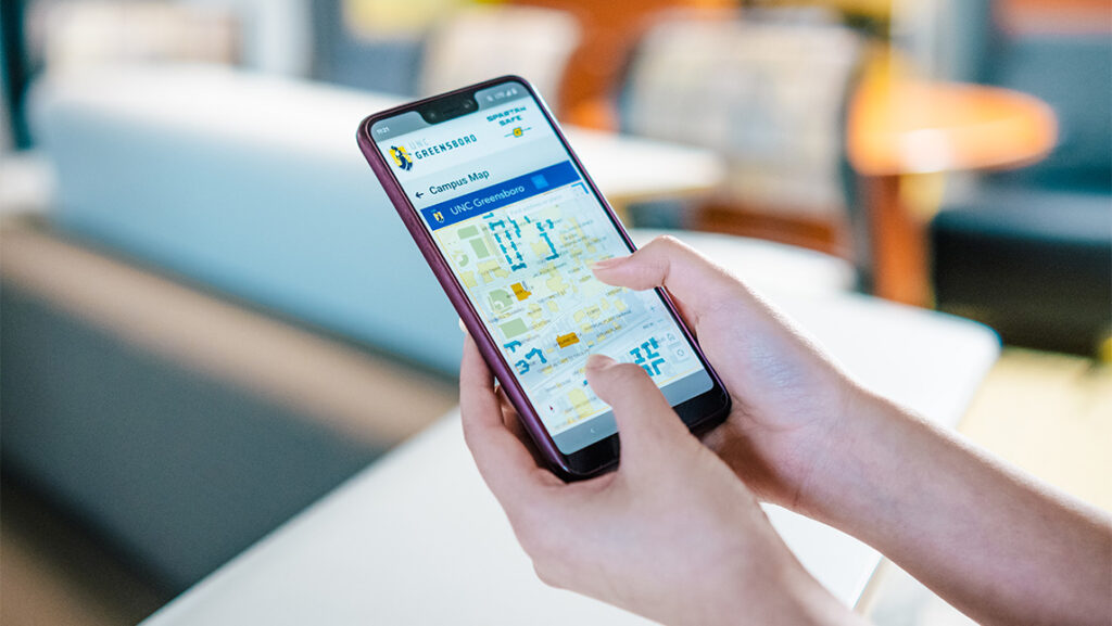 A close up on a person holding a phone with UNCG's Spartan Safe app open.