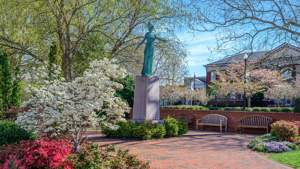 Flowering bushes and trees around the UNCG Minerva statue.