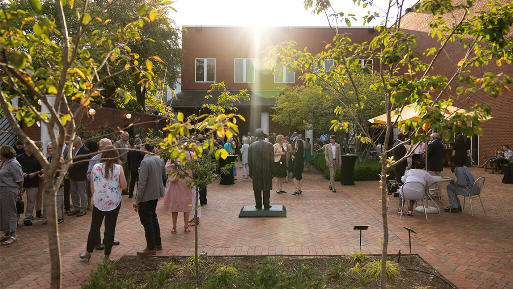 A crowd of people in dress clothes gather in the courtyard of UNCG Weatherspoon Art Museum.