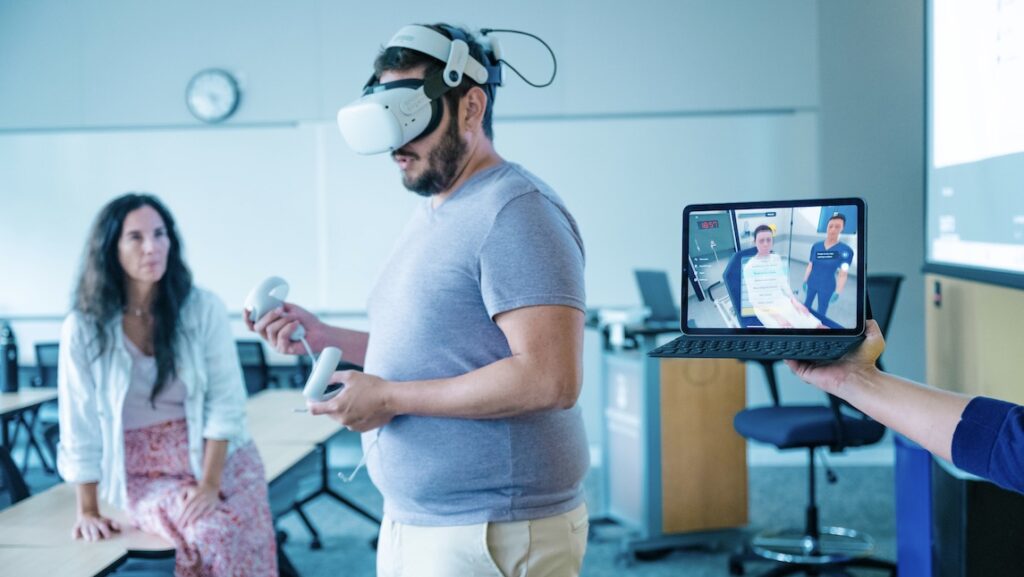 A male student in a classroom setting using the Virtual Reality monitor.