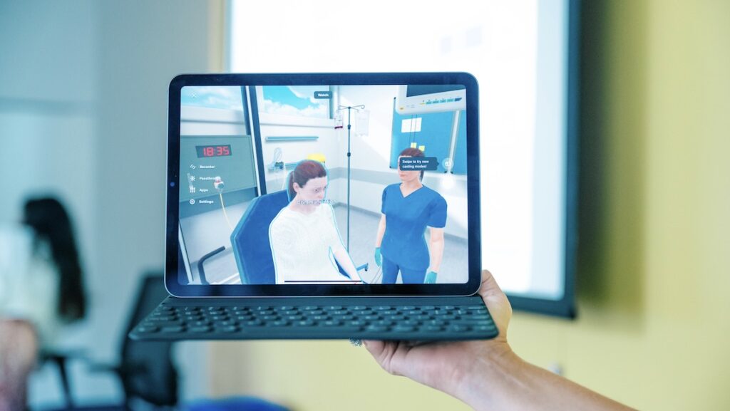 Photo of someone holding a small computer with Virtual Reality represented on the screen.