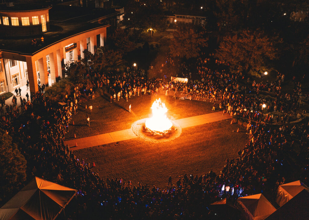 Kaplan Lawn at night full of people around a large bonfire, photographed from above. 