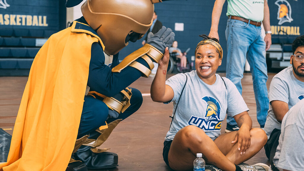 A UNCG student gives Spiro the mascot a high five.