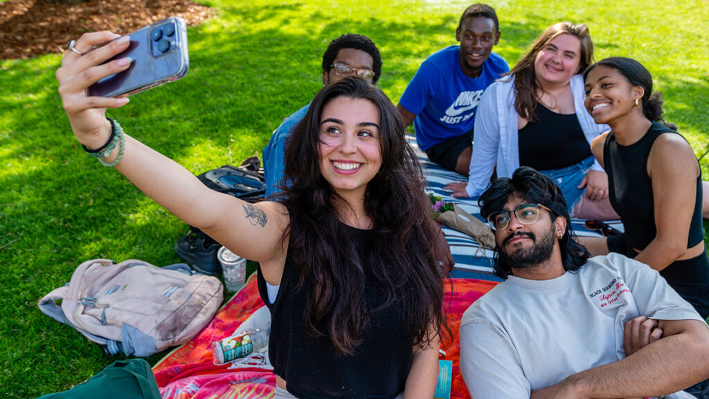 Students take a group selfie on the lawn of UNCG.