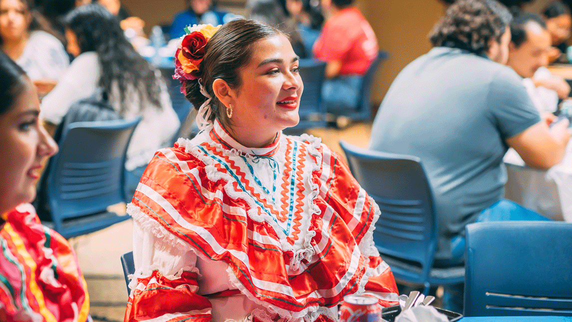 A UNCG student dressed in traditional Mexican regalia looks ahead