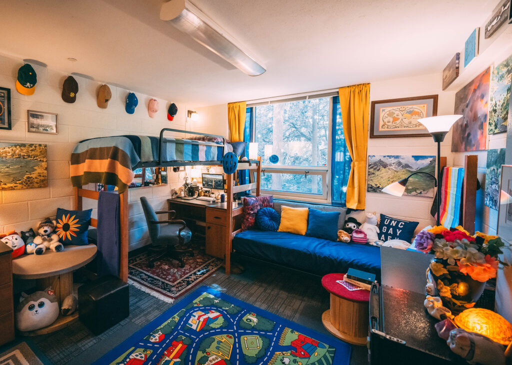 Dorm room decorated with colorful rugs, blue and gold colors and lots of wall hangings