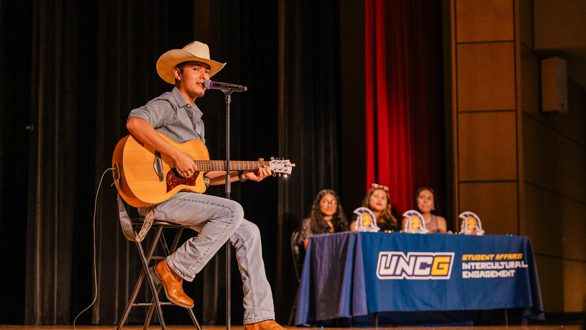 UNCG student plays guitar on stage during talent show