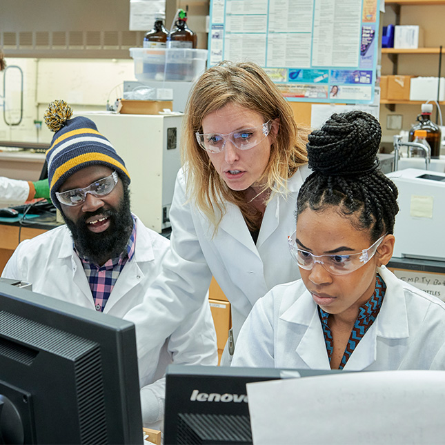 Professor works with grad students in a lab.
