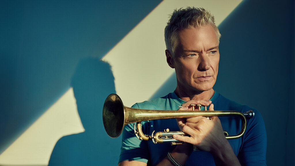 Musician Chris Botti holds a trumpet in a promotional image.