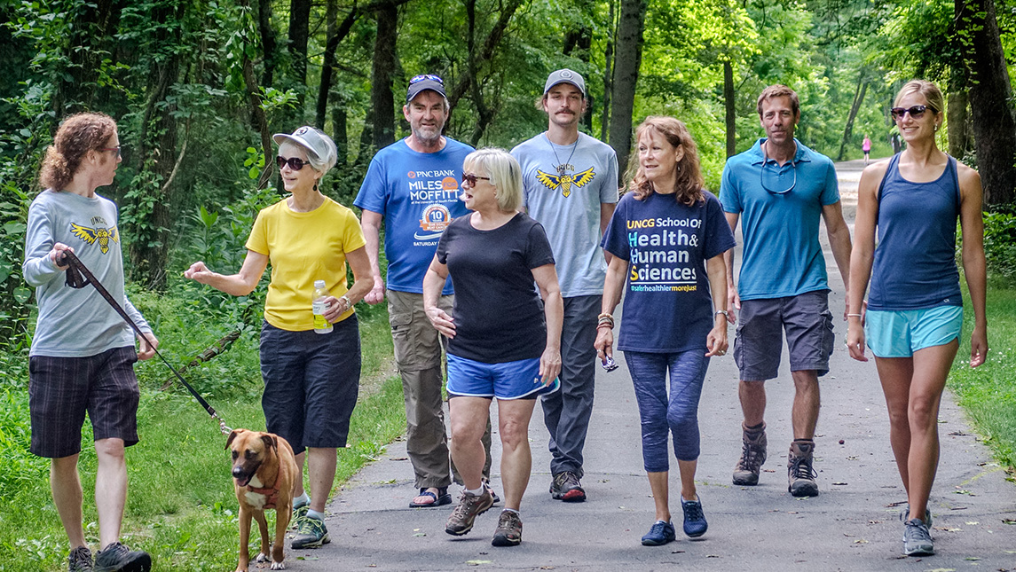 A group of people walk along a trail with a dog.