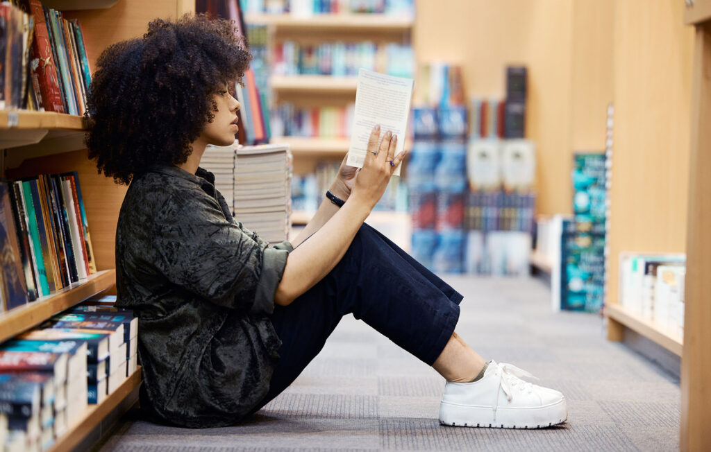 Student sitting on floor in library.
