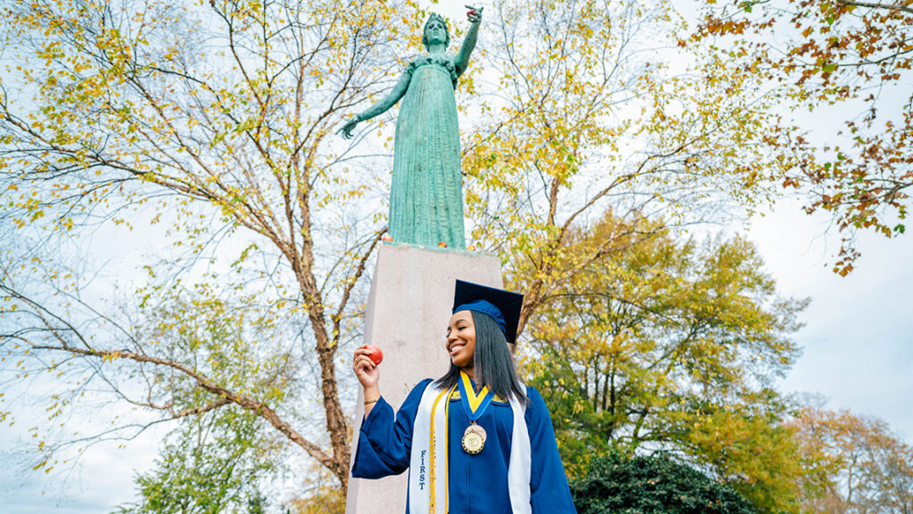 Williams holds an apple in front of the Minerva statue.