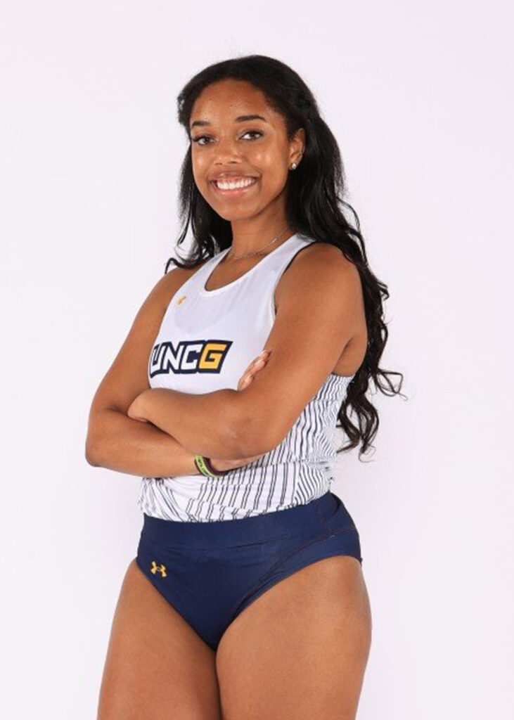 UNCG Women's track athlete stands with arms crossed.