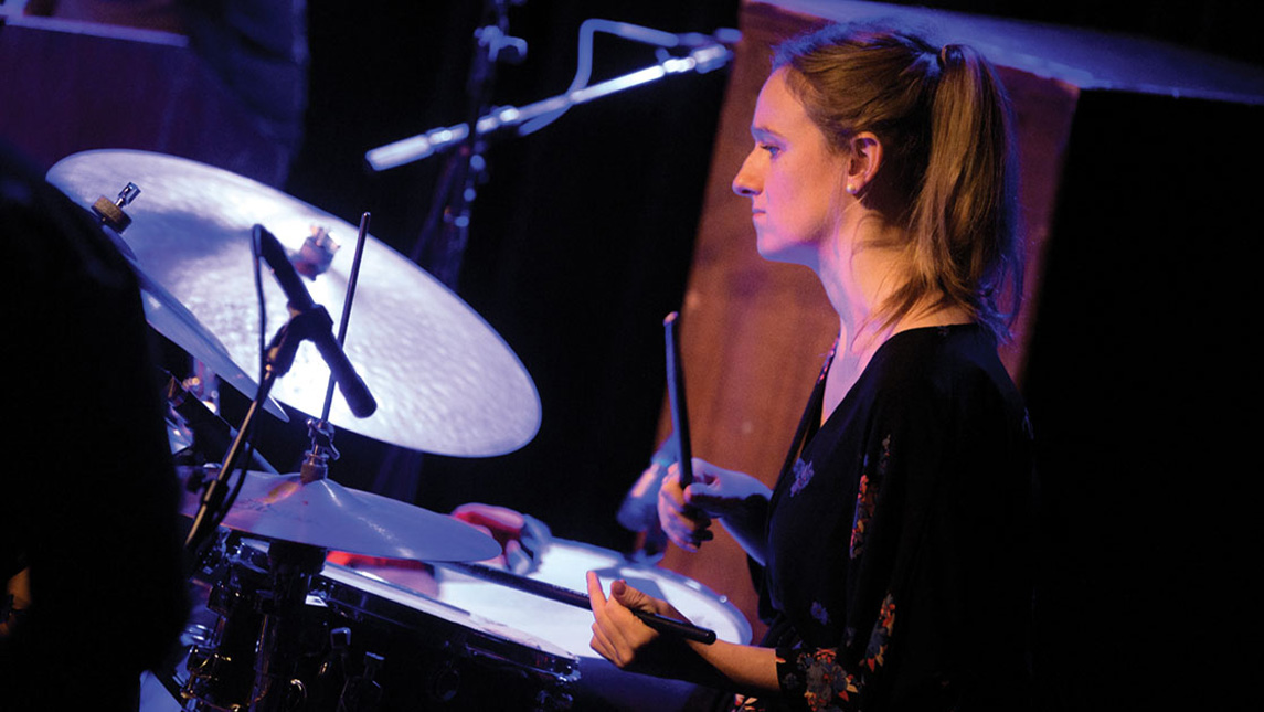 Sarah Gooch sits in front of a drum set