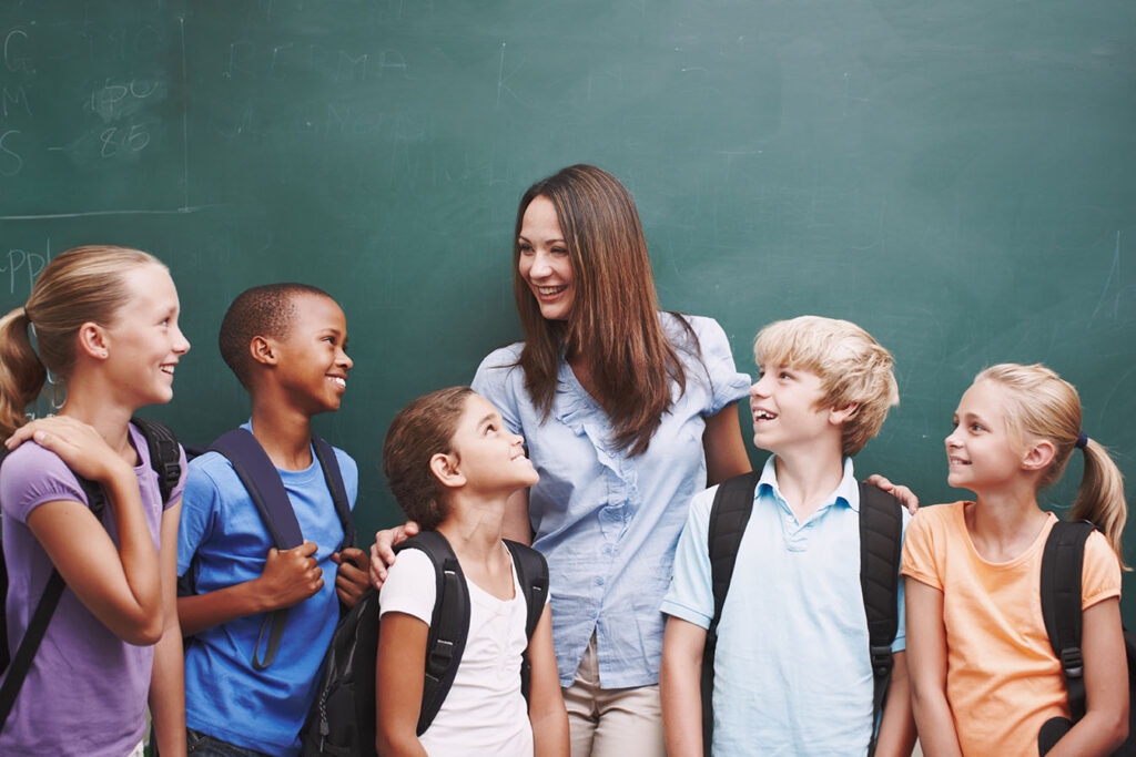 Librarian leading group of five children in front of chalkboard.