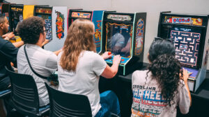 UNCG students play with mini arcade machines on a table.