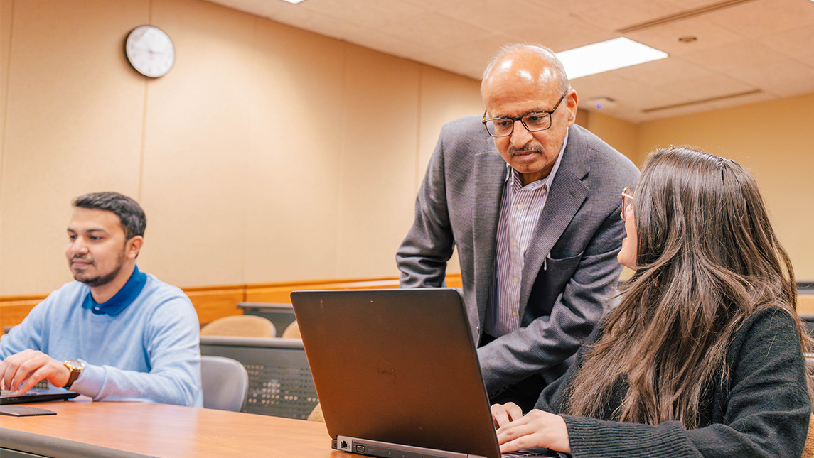 Dr. Prashant Palvia looks over the work on UNCG doctoral student Katelyn Walls' laptop.