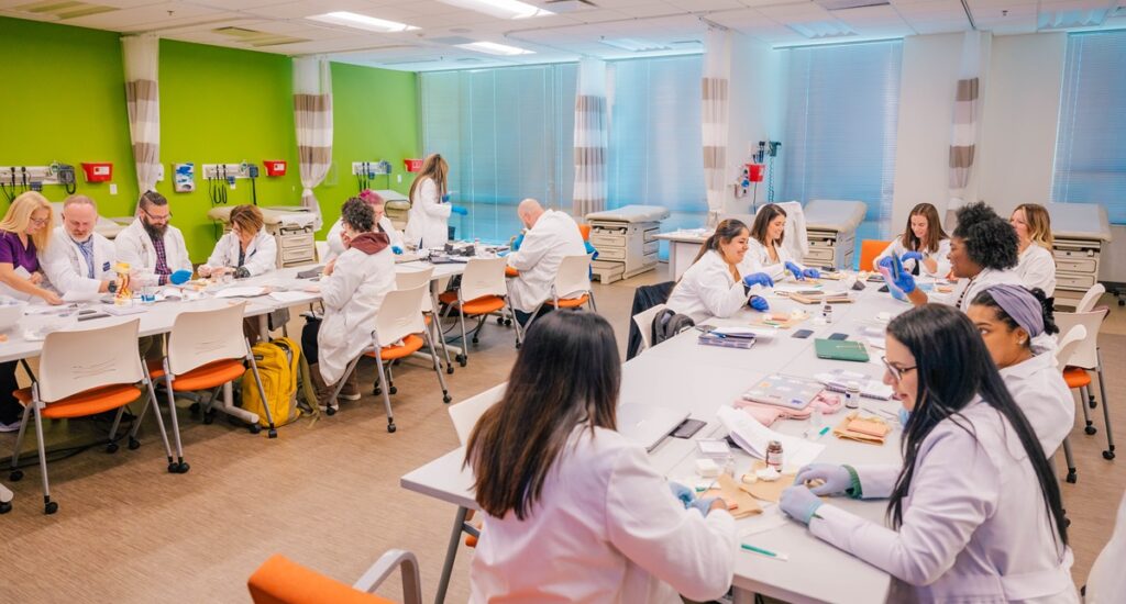 15 nursing students sitting at tables in a lab