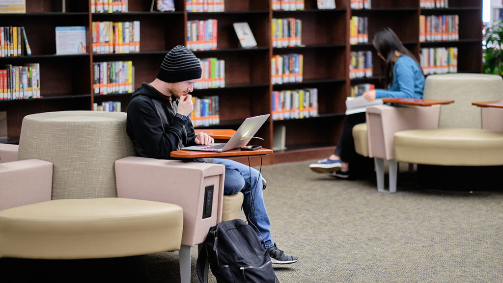 Students sit with their laptops in the UNCG Jackson Library.