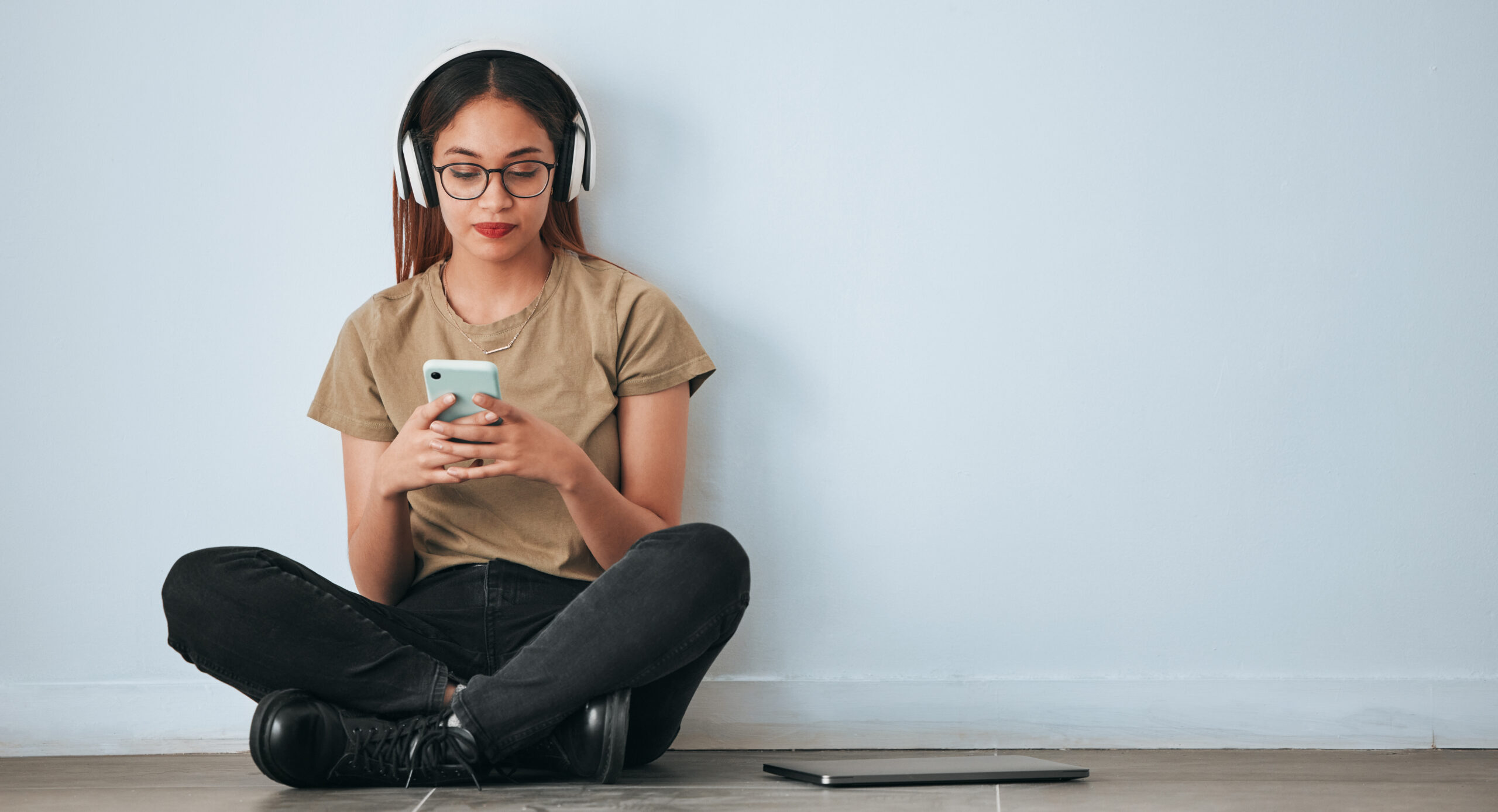 Woman sits on the ground with headphones on