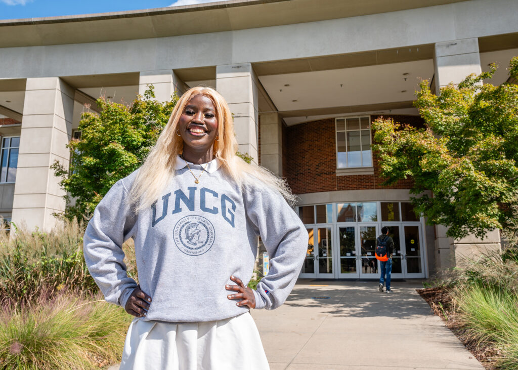 Student in a UNCG sweatshirt stands in front of the EUC.
