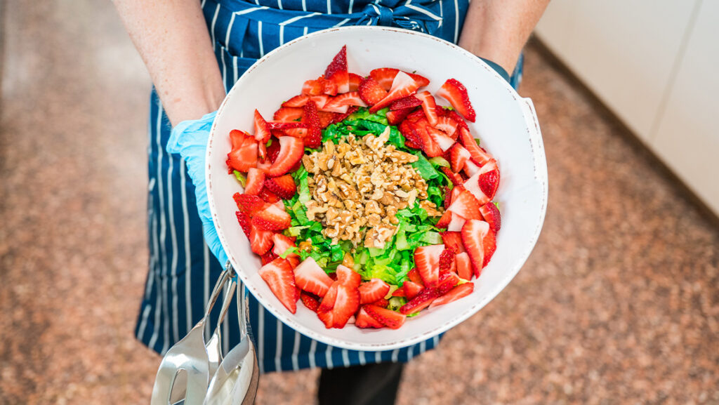 A person holds a bowl of fruit