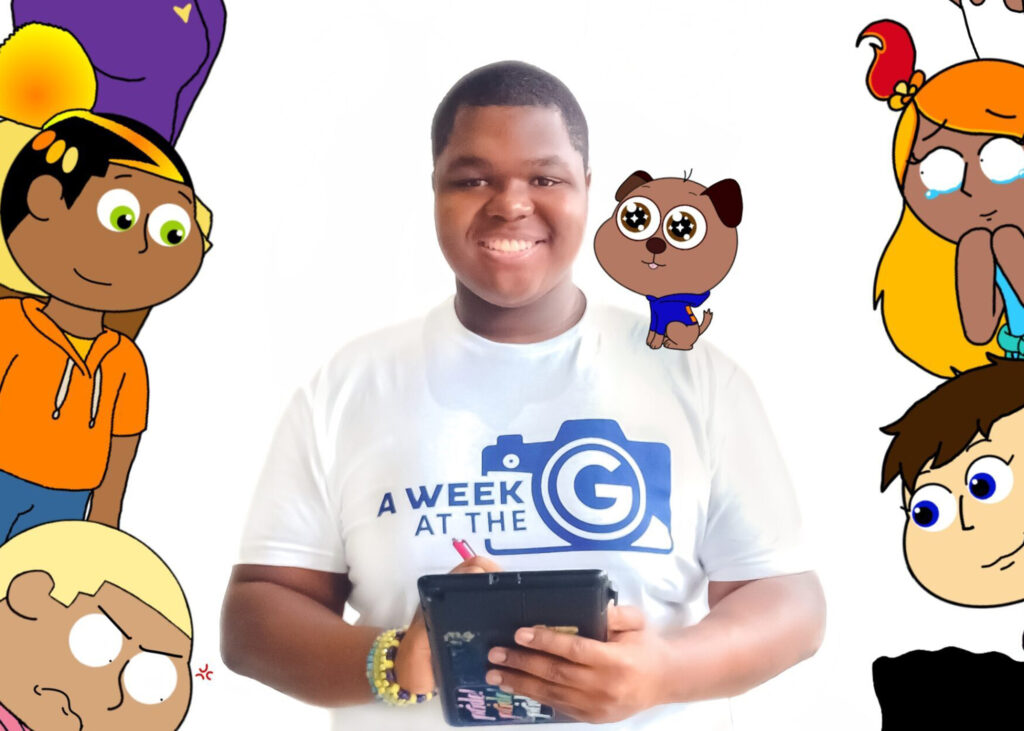 Student in "A Week at the G" t-shirt poses with a tablet & stylus with animated caricatures around him. 