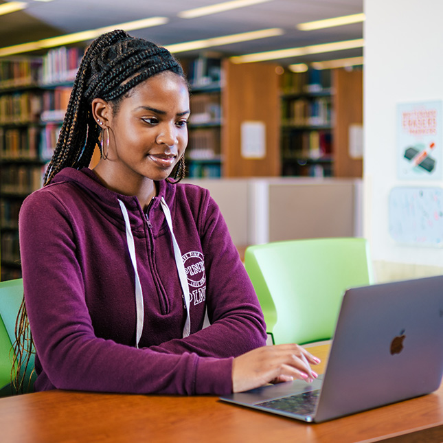 Student works on a laptop in a library.
