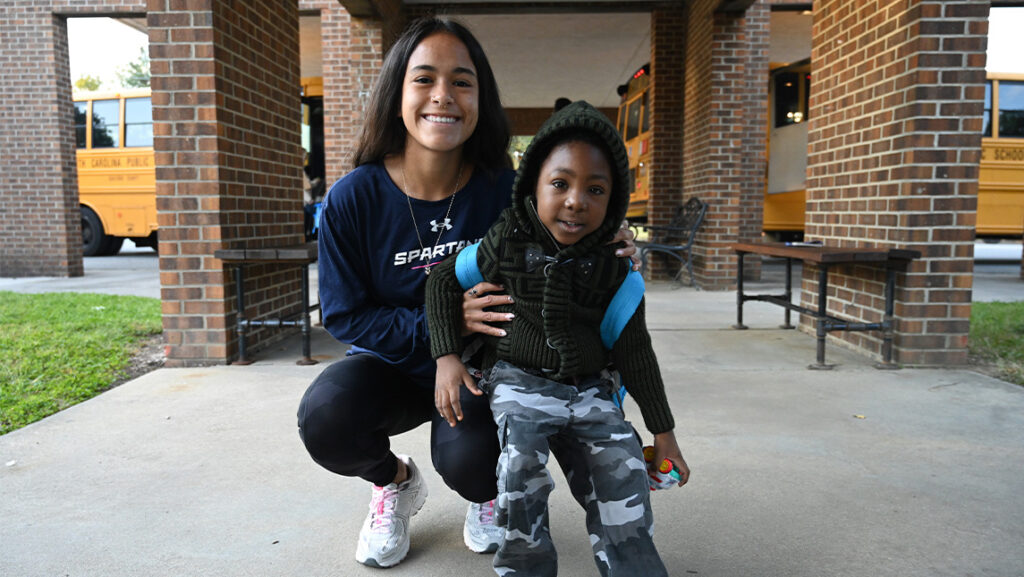 UNCG women’s soccer player Mel Herrara stands with a student from Gateway Education Center.