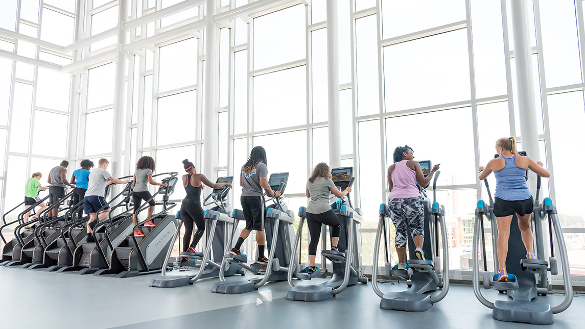 Students at a bank of treadmills facing the windows of the Kaplan Center.