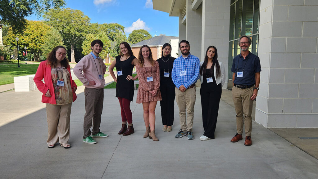 A group of individuals stand outdoors wearing name badges.