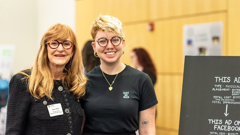 Dr. Dianne Welsh stands with a UNCG student at an entrepreneurship poster display.