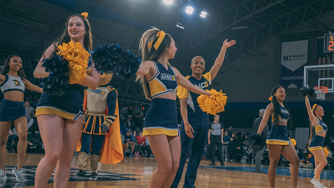 UNCG cheer performs on the basketball court at the Greensboro Coliseum.