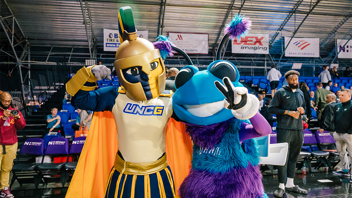 UNCG mascot Spiro flexes muscles with Greensboro Swarm mascot.
