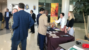 Representatives of local organizations talk to DARPA Connect conference participants at their tables in the UNCG JSNN atrium.