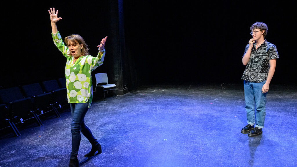UNCG alumna Beth Level performs with her hands in the hair. A student looks at her.